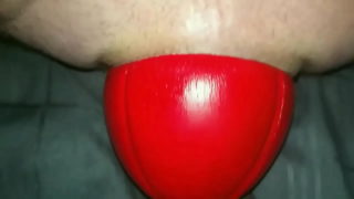 Riesiger, 12 cm breiter roter Fußball, der in Zeitlupe aus nächster Nähe aus meinem Arsch rutscht